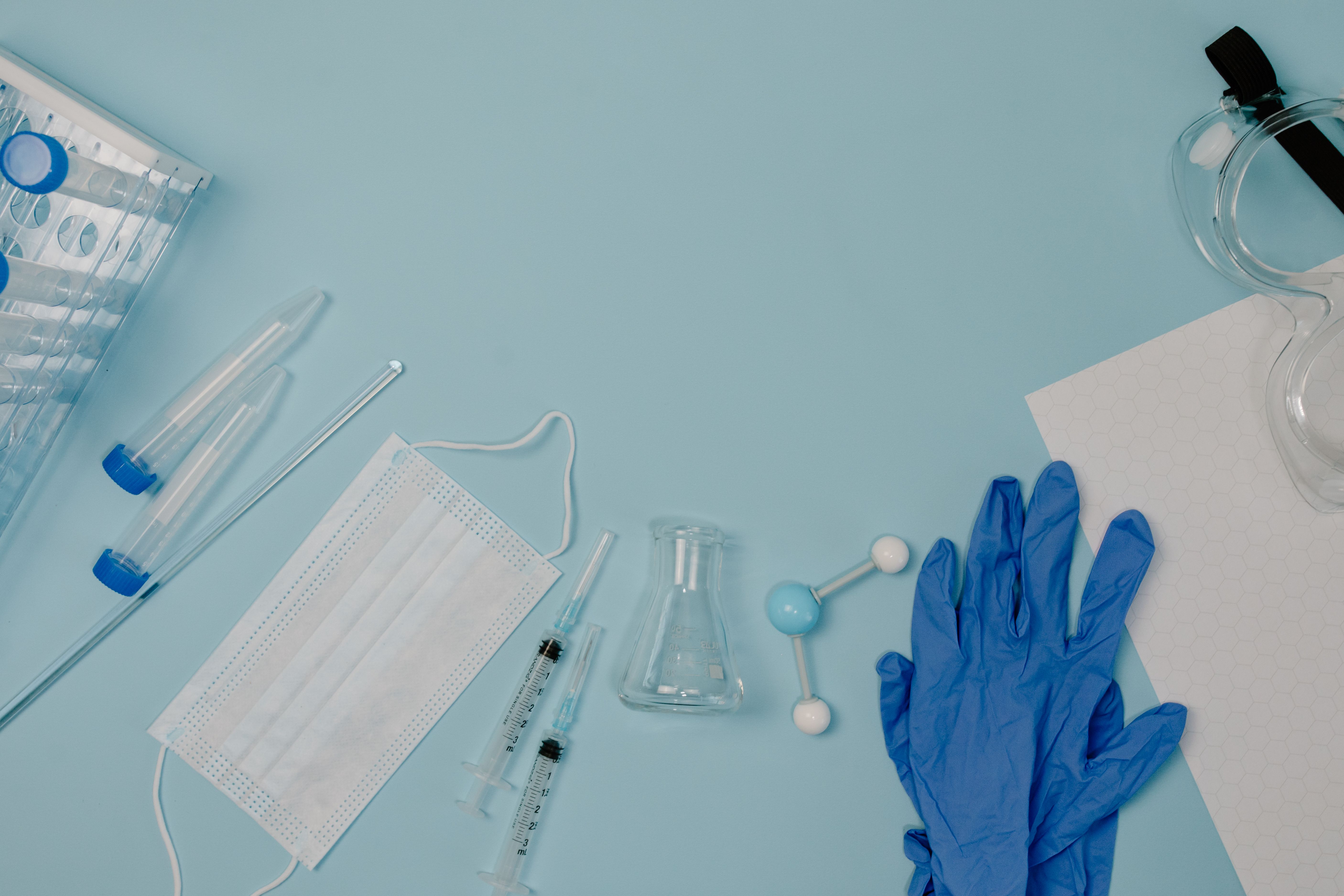 Materiales de laboratorio y guantes sobre superficie clínica azul
